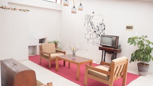 Een woonkamer met een televisie, houten meubels, een rood tapijt en een muurschildering.