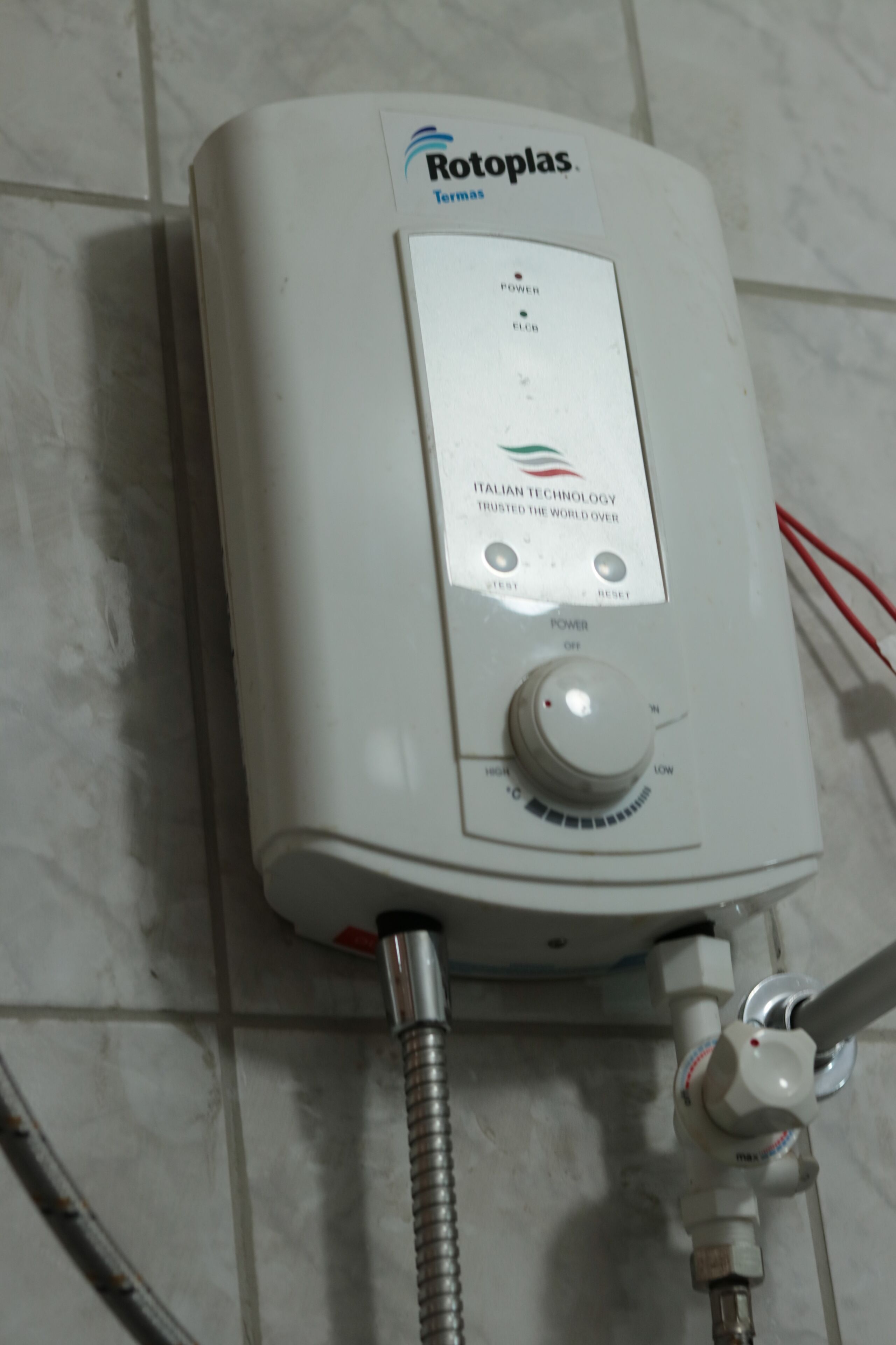 Calentador de agua Rotoplas blanco con panel de control, conectado a una manguera flexible.