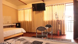 Een hotelkamer met een bed, een bureau, een stoel, een televisie en een raam met gordijnen.