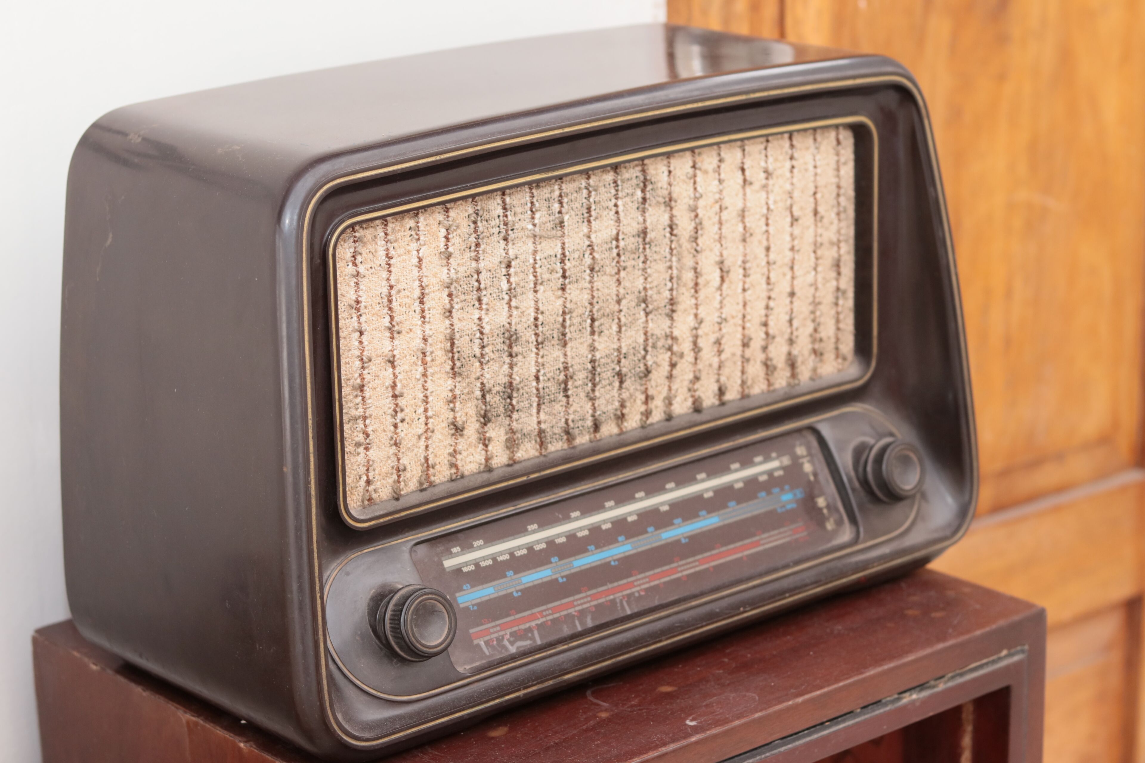 Um rádio antigo sobre um suporte de madeira.