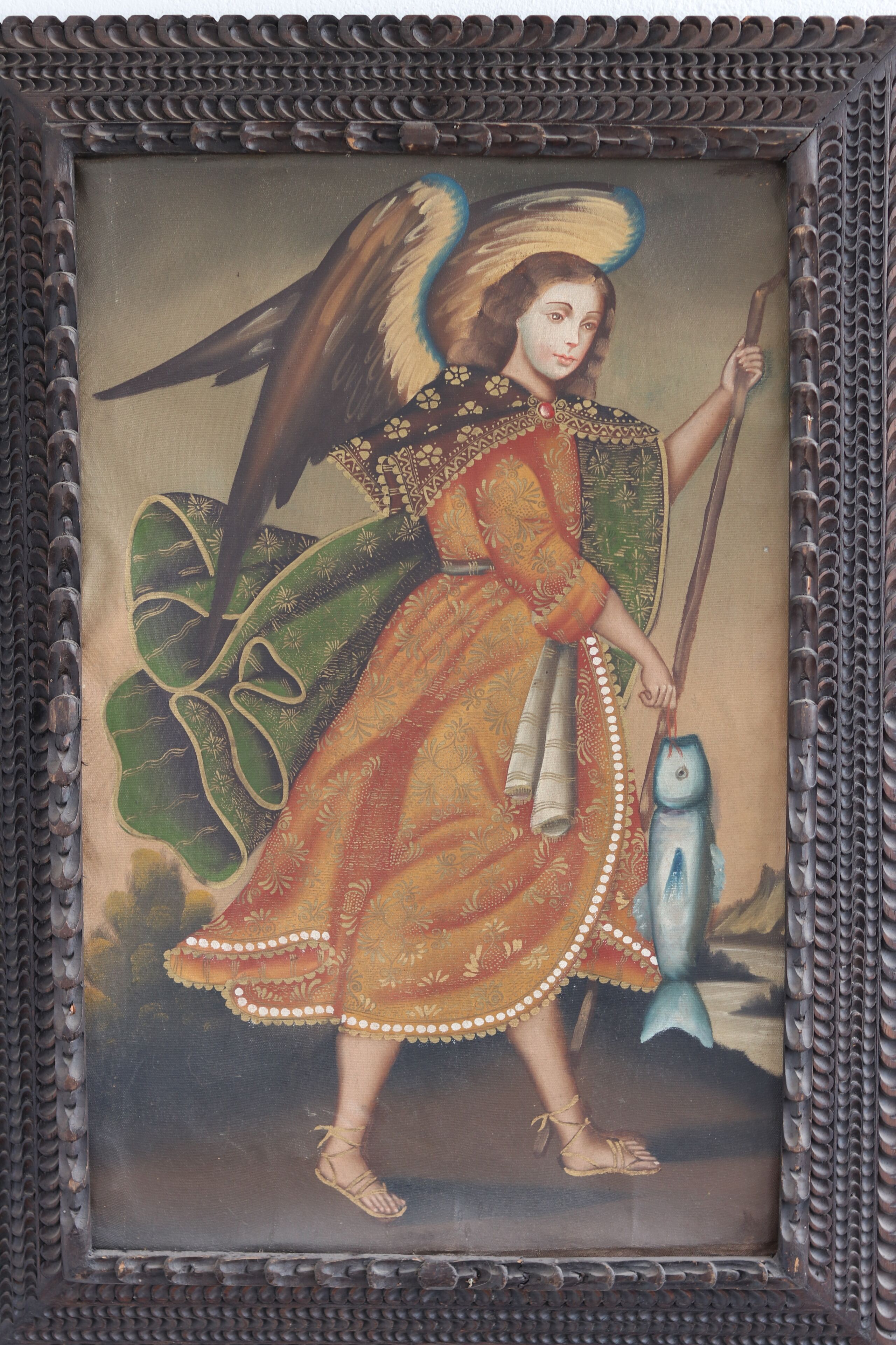 A framed artwork with an angelic figure, a fish, and a staff.