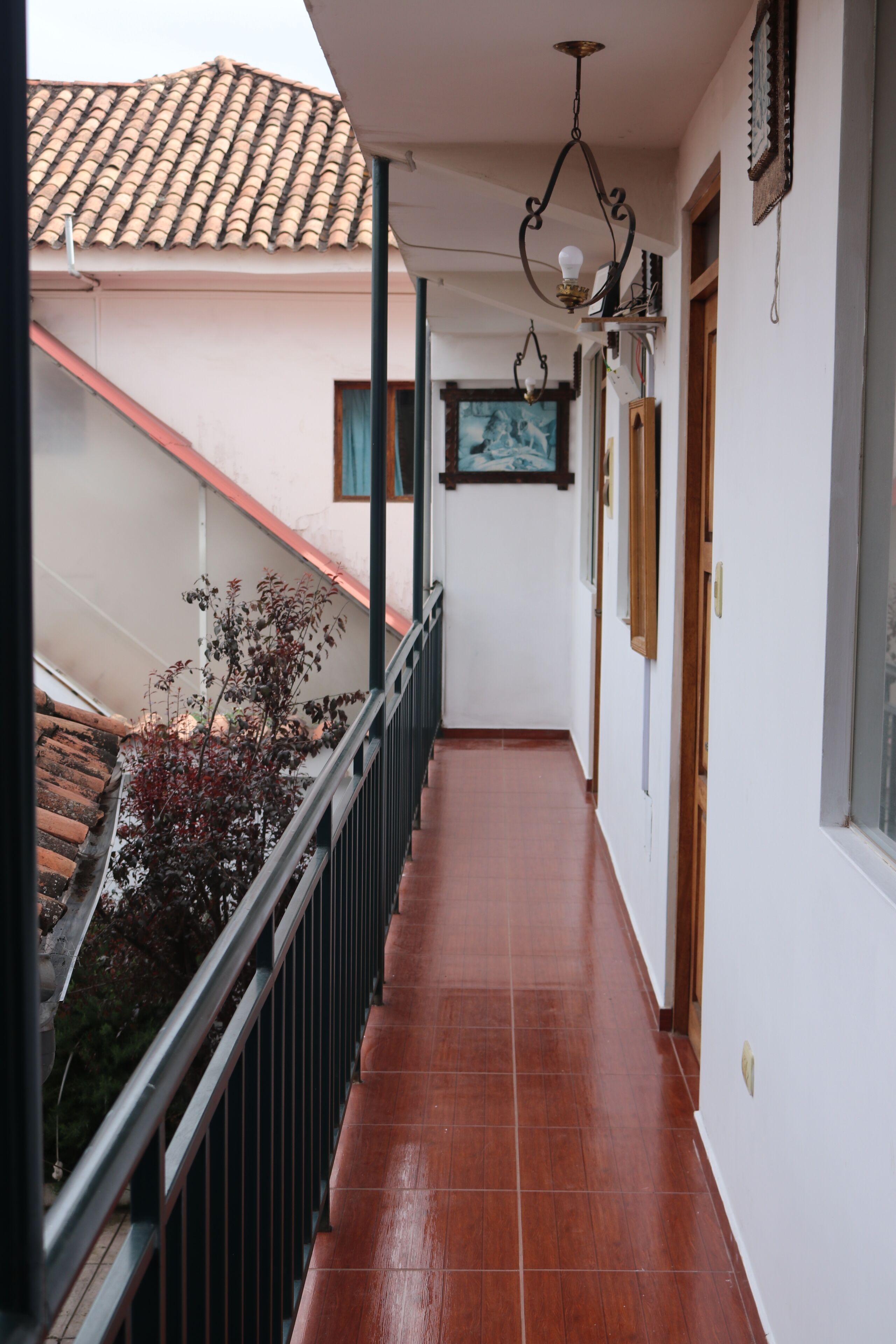 A corridor with a tiled floor, a railing, and a ceiling light fixture.