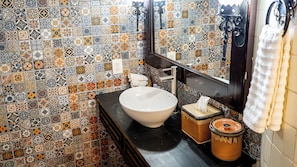 A bathroom with a tiled wall, a sink, a mirror, and a towel rack.