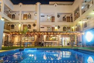 Un hotel de varios pisos con piscina, asientos al aire libre y balcones.