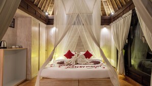 A room with a bed, a bedside table, and a window with curtains.