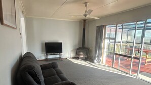 Una sala de estar con sofá, televisión de pantalla plana, chimenea y vistas a una terraza.