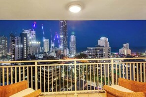 A balcony with wicker furniture, a cityscape view at night, and a railing. - Salt & Sky Arcade - Sleeps 12 (Surfers Paradise)