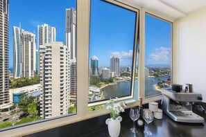 A room with a large window overlooking a cityscape with high-rise buildings and a river. - Salt & Sky Arcade - Sleeps 12 (Surfers Paradise)