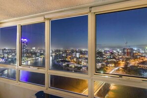 A view through a window with multiple panes, each displaying a nighttime cityscape with buildings, roads, and a river. - Salt & Sky Arcade - Sleeps 12 (Surfers Paradise)