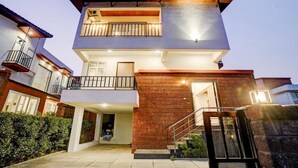 Un edificio de dos pisos con un balcón, una escalera y una puerta que da a la entrada.