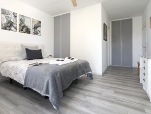 A modern bedroom with a bed, grey bedding, a bedside table, and a wardrobe. - Sunstay Lima Flat Malaga (Málaga)