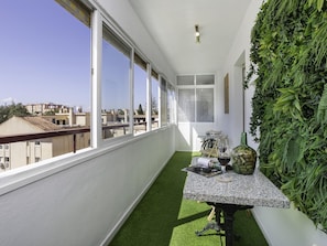 A balcony with a table, chairs, and a green wall. - Sunstay Lima Flat Malaga (Málaga)