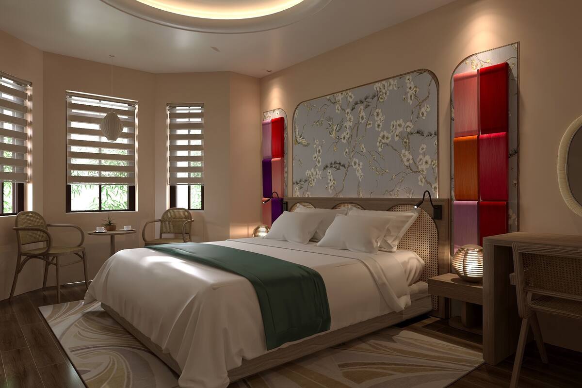 A modern bedroom with a bed, two chairs, a small table, and a decorative mirror.