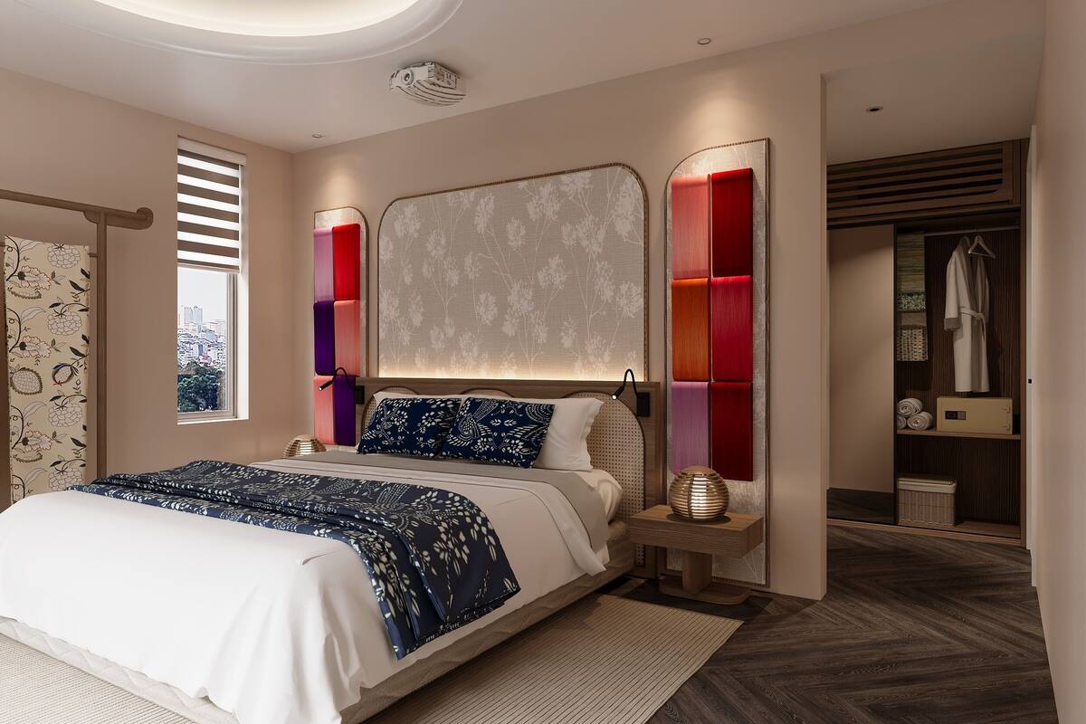 A modern bedroom with a large bed, a headboard with a floral pattern, a bedside table with a lamp, and a view of the city through a window.