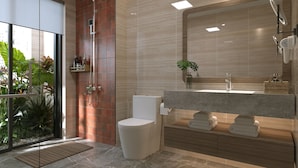 Ein modernes Badezimmer mit Duschabtrennung aus Glas, Toilette, Waschtisch mit Spiegel und Waschbecken.