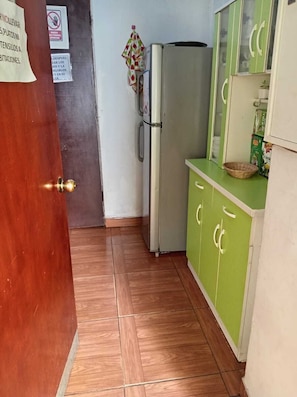 A kitchen with a refrigerator, cabinets, and a tiled floor. - Sofiya (Cusco)