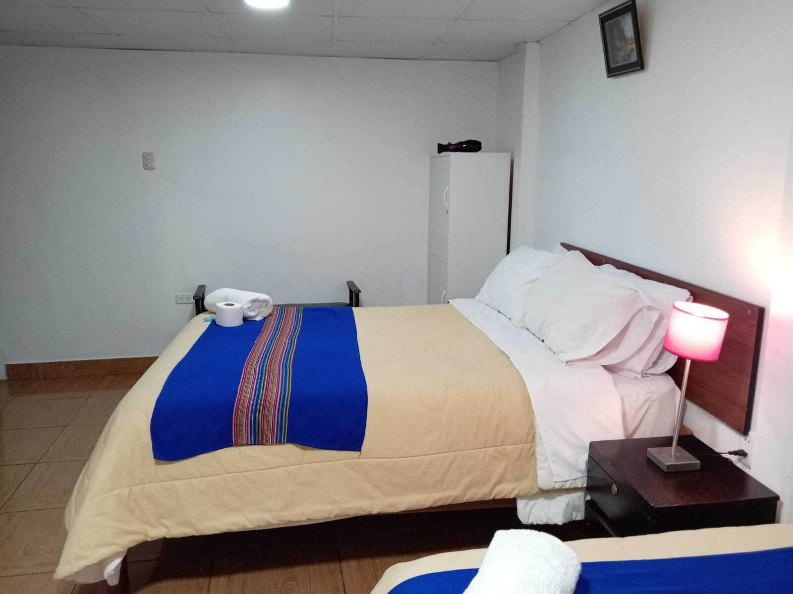 Una habitación de hotel con una cama, una lámpara de noche, un teléfono y un armario.