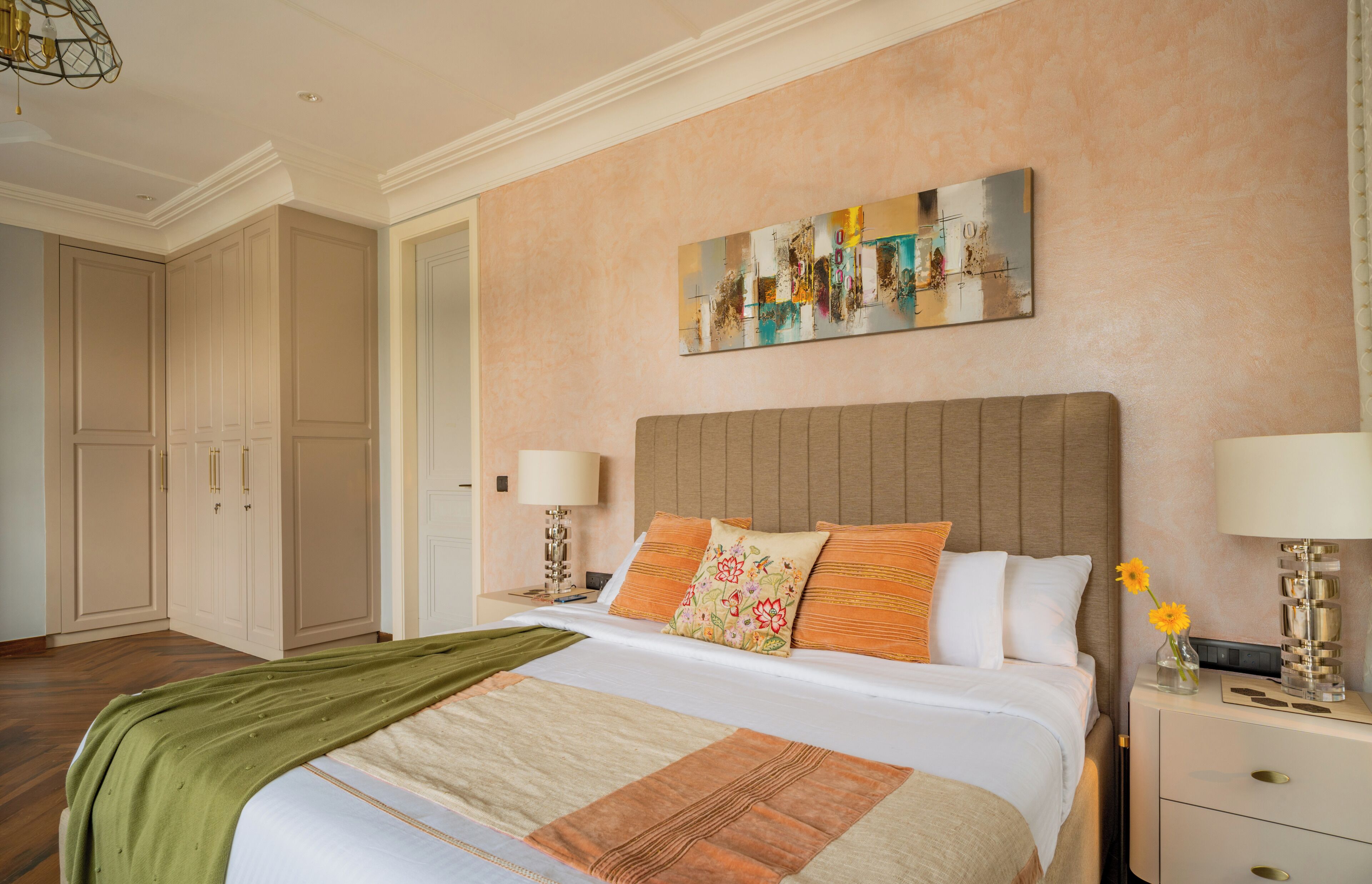A hotel room with a bed, nightstands, a painting, and a wardrobe.