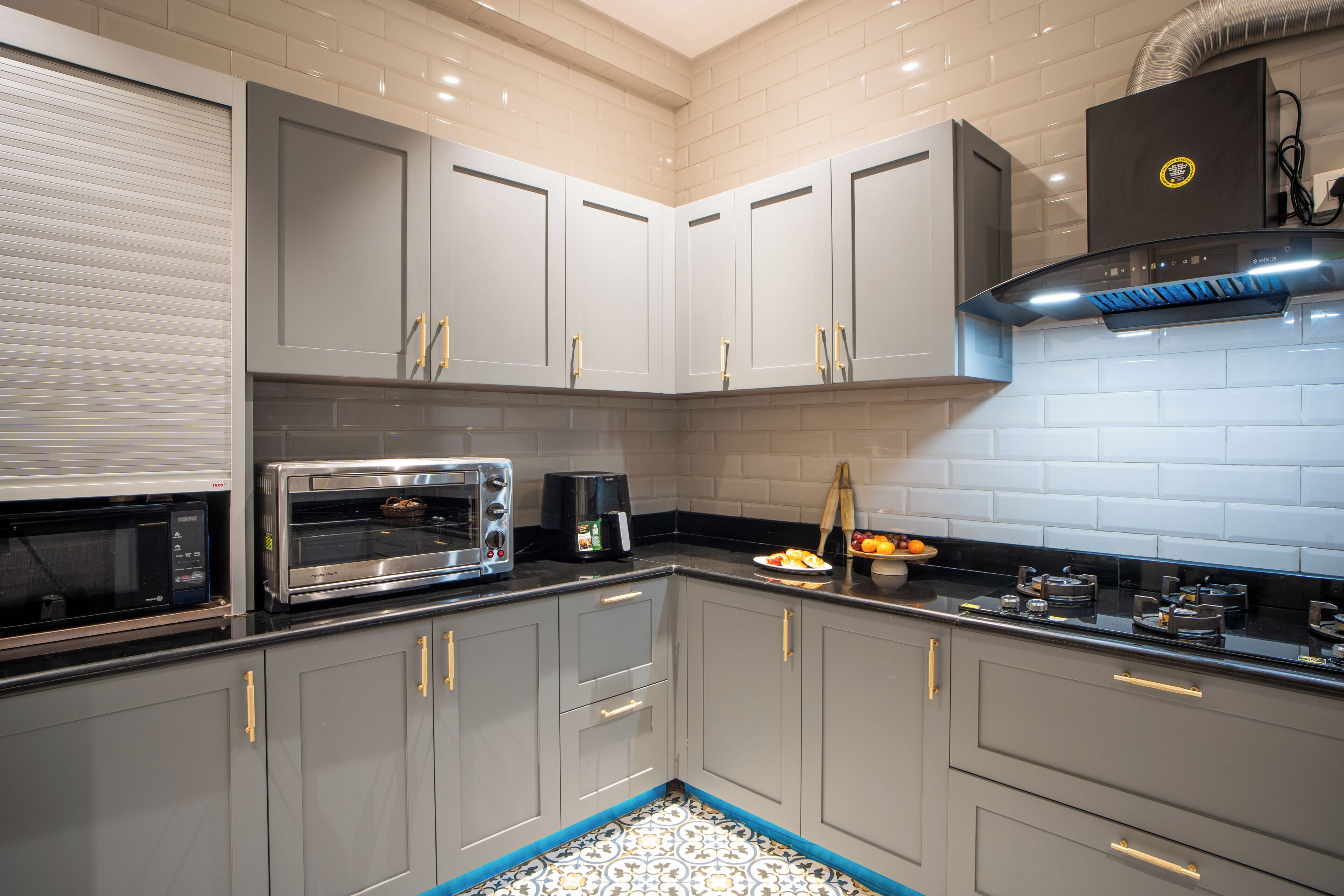 A modern kitchen with grey cabinets, a built-in microwave, a toaster oven, and a coffee maker.