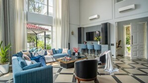 Un salón amplio con suelo a cuadros, un conjunto de sofás, una mesa de centro y un televisor montado en la pared.