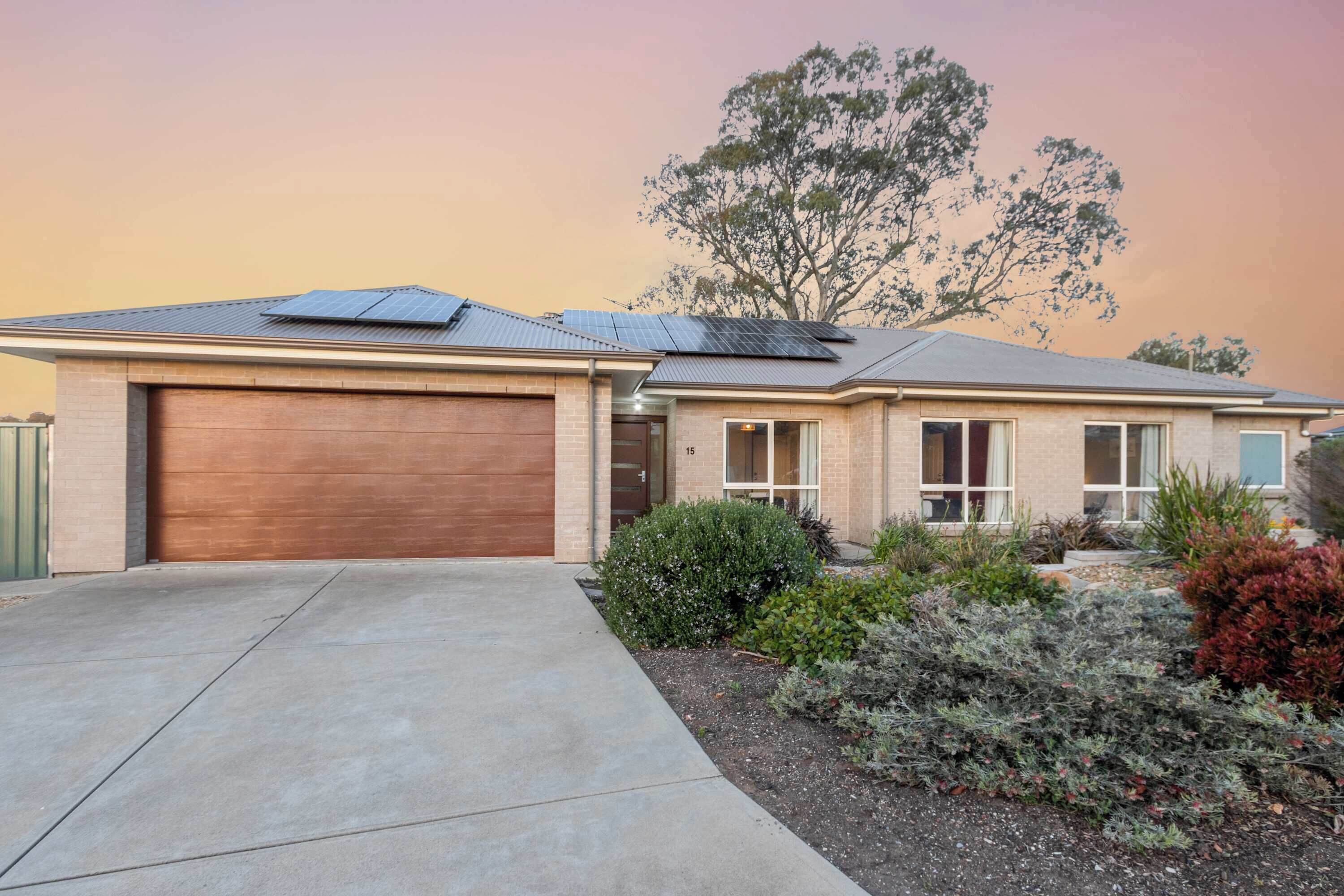 Une maison de plain-pied avec un garage, des panneaux solaires et un jardin bien entretenu.
