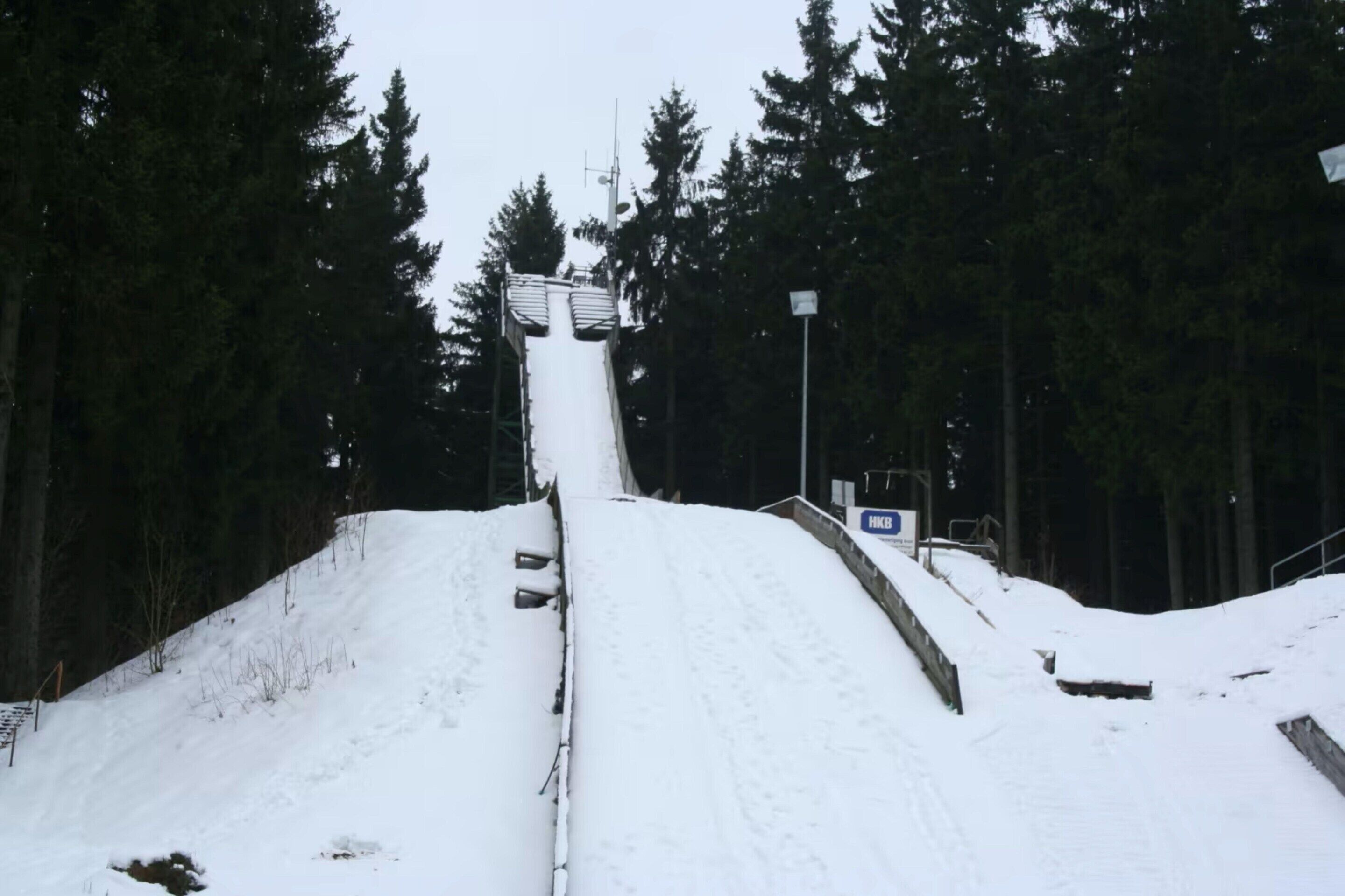 Pista de esquí nevada con un telesilla y una señal.