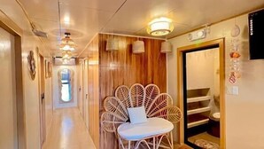 Un couloir doté d’un plancher en bois, d’une chaise en osier et d’une porte avec un miroir.