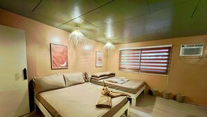Une chambre à coucher comprenant un lit, des tables de chevet, une fenêtre avec des stores et un climatiseur fixé au mur.