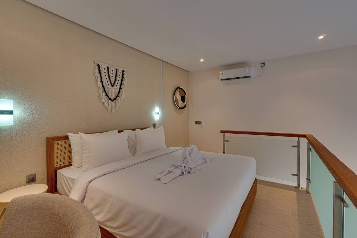 Ein Hotelzimmer mit Bett, einer Wandklimaanlage, einer runden Wanddekoration und einem Holzbalken.