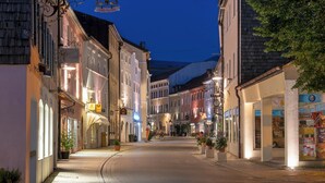 Eine enge Straße gesäumt von traditionellen europäischen Gebäuden mit Geschäften und einem klaren Himmel.