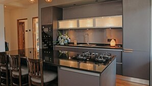 A modern kitchen with a central island, built-in appliances, and a dining area with chairs. - Stone Heaven Villa (Nuwara Eliya)