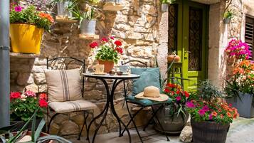 A stone wall with metal furniture, a green door, and potted plants.