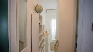 A narrow hallway with a door on the left, a globe on the wall, and a chair in the distance.