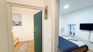 A bedroom with a bed, a window, a television, and a door leading to another room. - Casa Nora in Centre of Vodnjan (Vodnjan)