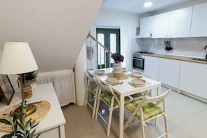 A dining area with a table set for four, a lamp, and a potted plant. - Casa Nora (Vodnjan)