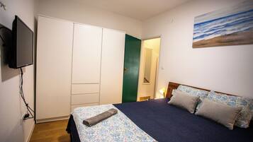 Une chambre à coucher avec un lit, une télévision, une armoire et un tableau au mur.