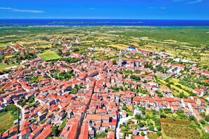 Eine Vogelperspektive auf eine Stadt mit roten Dächern, einem markanten Turm und umgebenden grünen Feldern.