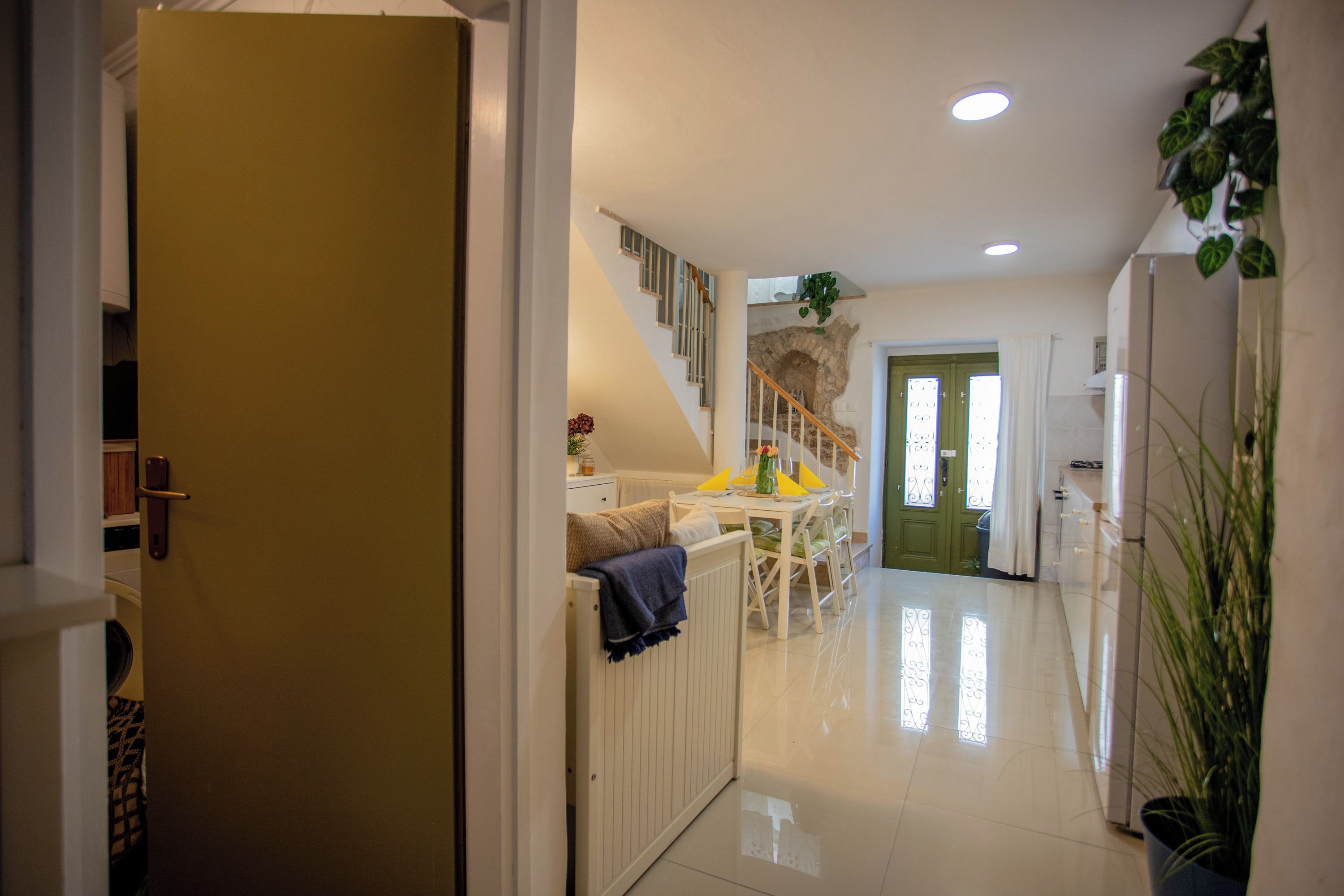 A hallway leading to a dining area with a staircase, a radiator, and a potted plant.