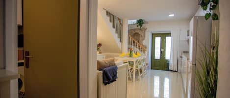 Un couloir menant à une salle à manger, avec un escalier, un radiateur et un pot de fleurs.