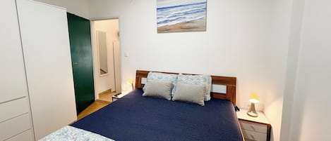 Un dormitorio con una cama, dos lámparas de noche, una mesita de noche, una puerta y un cuadro en la pared.