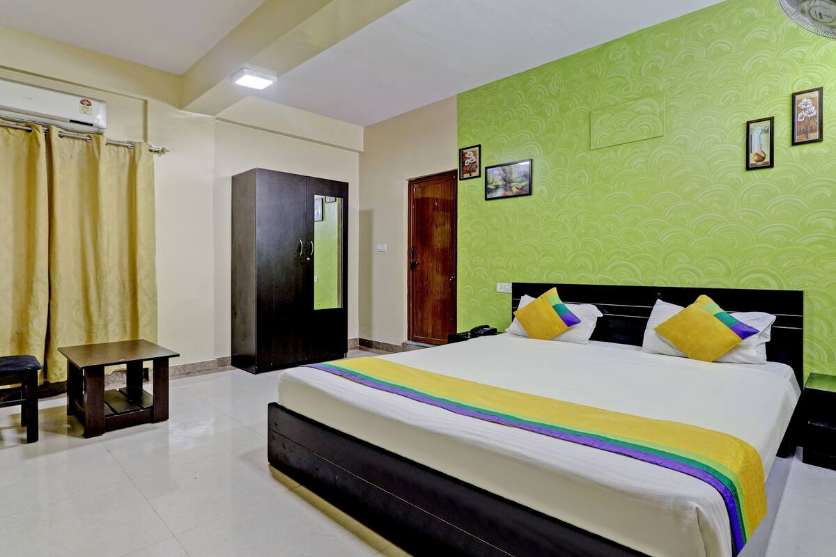 A hotel room with a bed, a small table, a wardrobe, and a door.