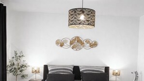 Een moderne slaapkamer met een groot bed, bedlampen, een decoratief wandobject en een potplant.
