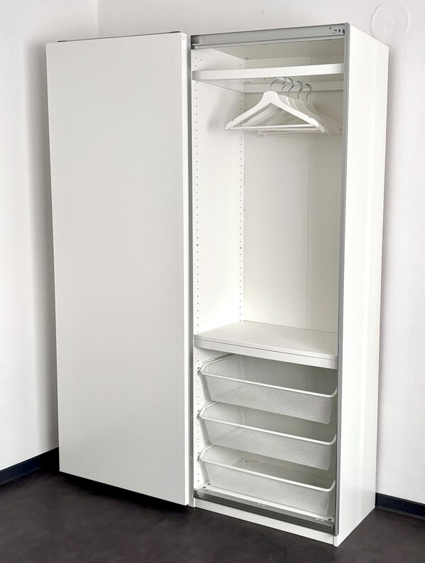 A white walk-in closet with open doors, featuring hanging space and wire shelves. - Ferienhaus Schieferland - Your vacation home between the Moselle and the Nürburgring (Müllenbach)