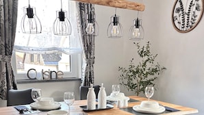 Een eethoek met een houten tafel, zwarte stoelen, hangende lampen en uitzicht op het buitengebied.