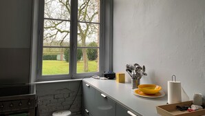 A kitchen with a large window, a stove, a sink, and a countertop with kitchenware. - Family home (Bussus-lès-Yaucourt)