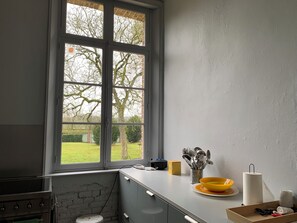 A kitchen with a large window, a stove, a sink, and a countertop with kitchenware. - Family home (Bussus-lès-Yaucourt)