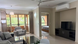Sala moderna com sofá, TV e área de refeições.