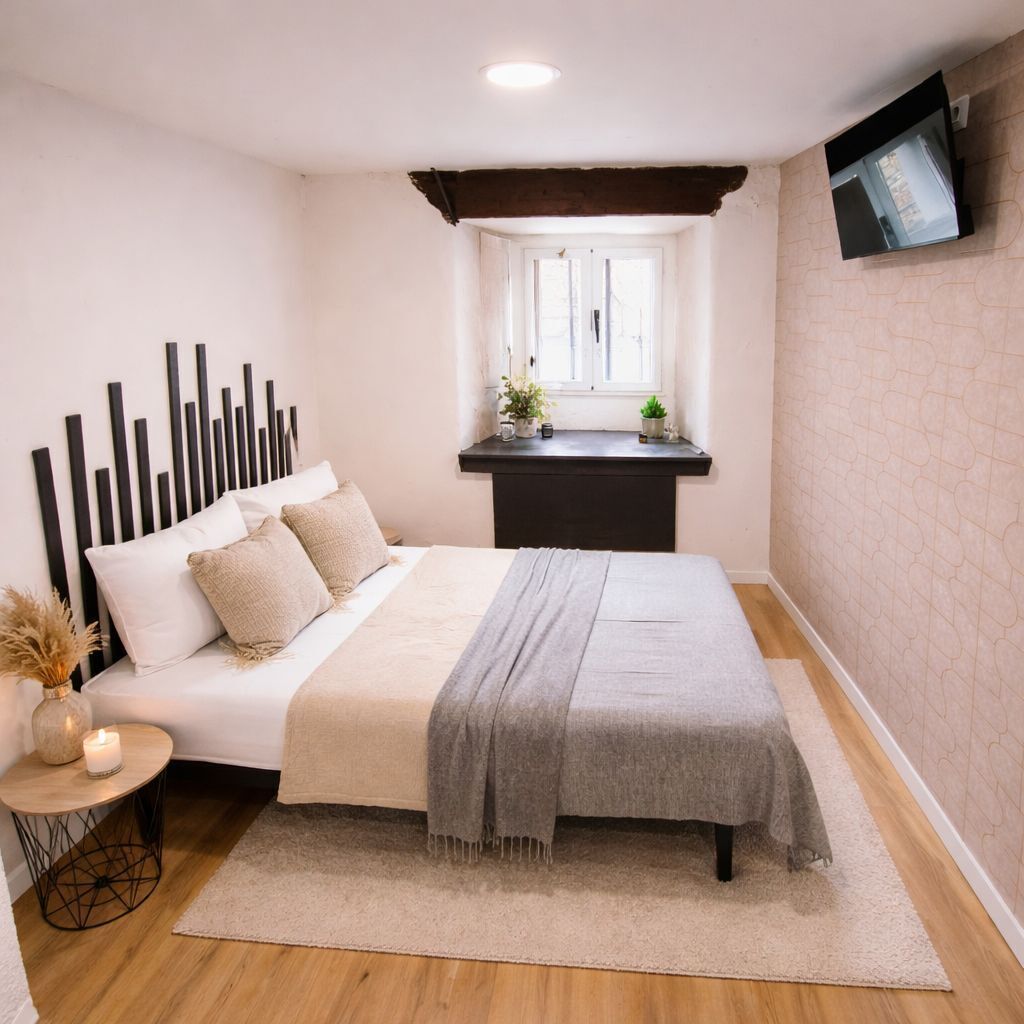 A bedroom with a bed, bedside table, and a window.