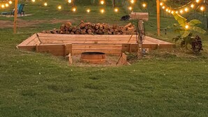 A wooden structure with a fire pit, surrounded by a grassy area and string lights. - 3-bedroom cabin in Madisonville TN (Madisonville)