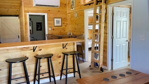 A wooden interior with a bar area, stools, a table with a remote control, and a ladder. - 3-bedroom cabin in Madisonville TN (Madisonville)